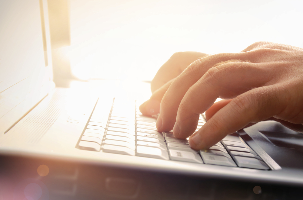 Man's hands typing on laptop keyboard